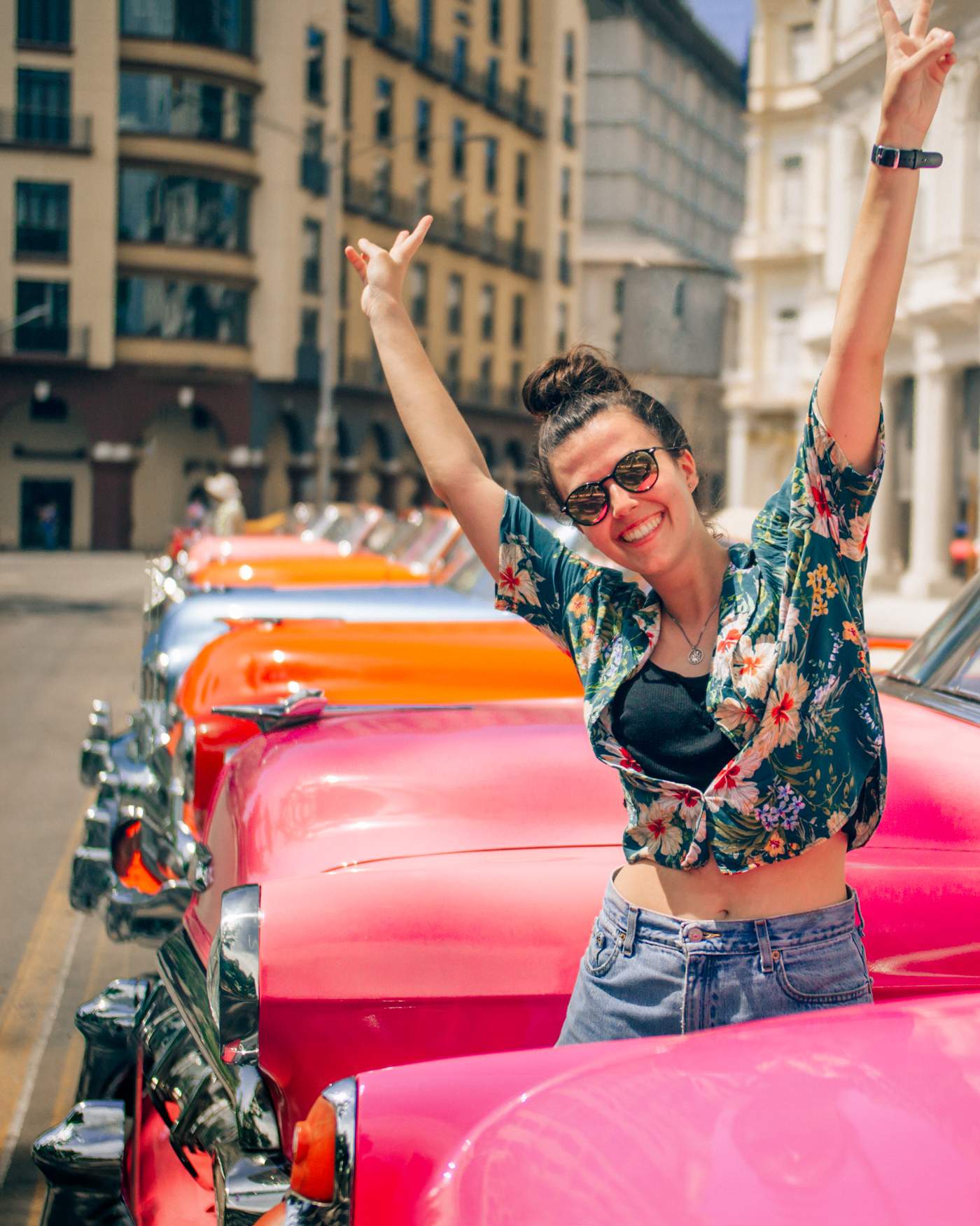 Katie standing between old American cars in Havana