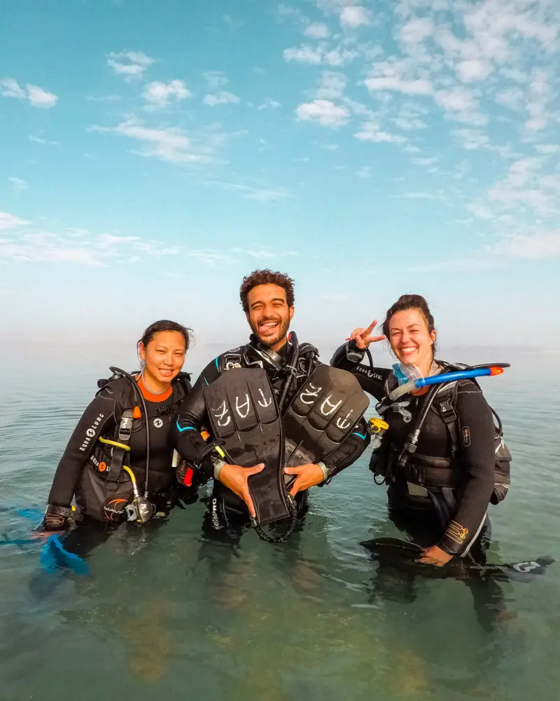 Three divers photographed post-dive in a remote lagoon.